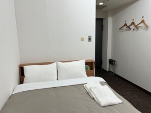 Una habitación de hotel con cama, mesita de noche, reloj y radiador.