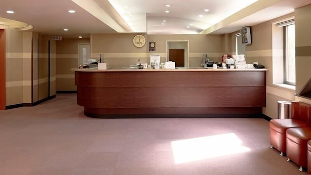 A reception area with a wooden reception desk, a clock, and a window on the right. - Hotel Royal Oak Gotanda (Tokyo)