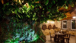 Un restaurant doté d’un mur en pierre rustique, de tables et de chaises en bois.