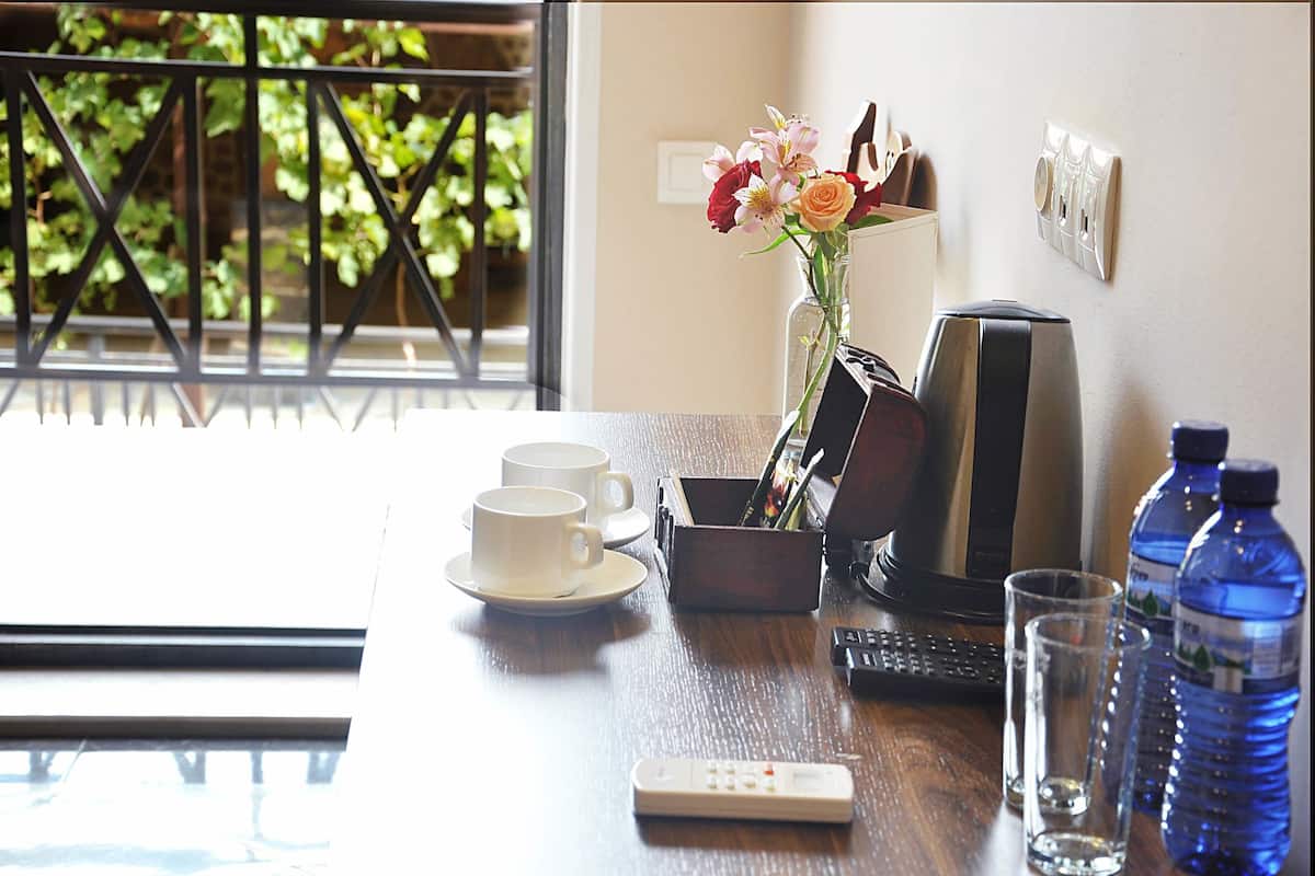 Una mesa de madera con un florero, dos tazas blancas, un control remoto, un teclado y dos botellas de agua.