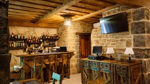 Un coin bar au décor rustique, avec des meubles en bois, des murs en pierre et un téléviseur fixé au mur.