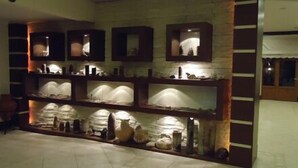 Un hall con pared de piedra y estanterías que exhiben diversos objetos.