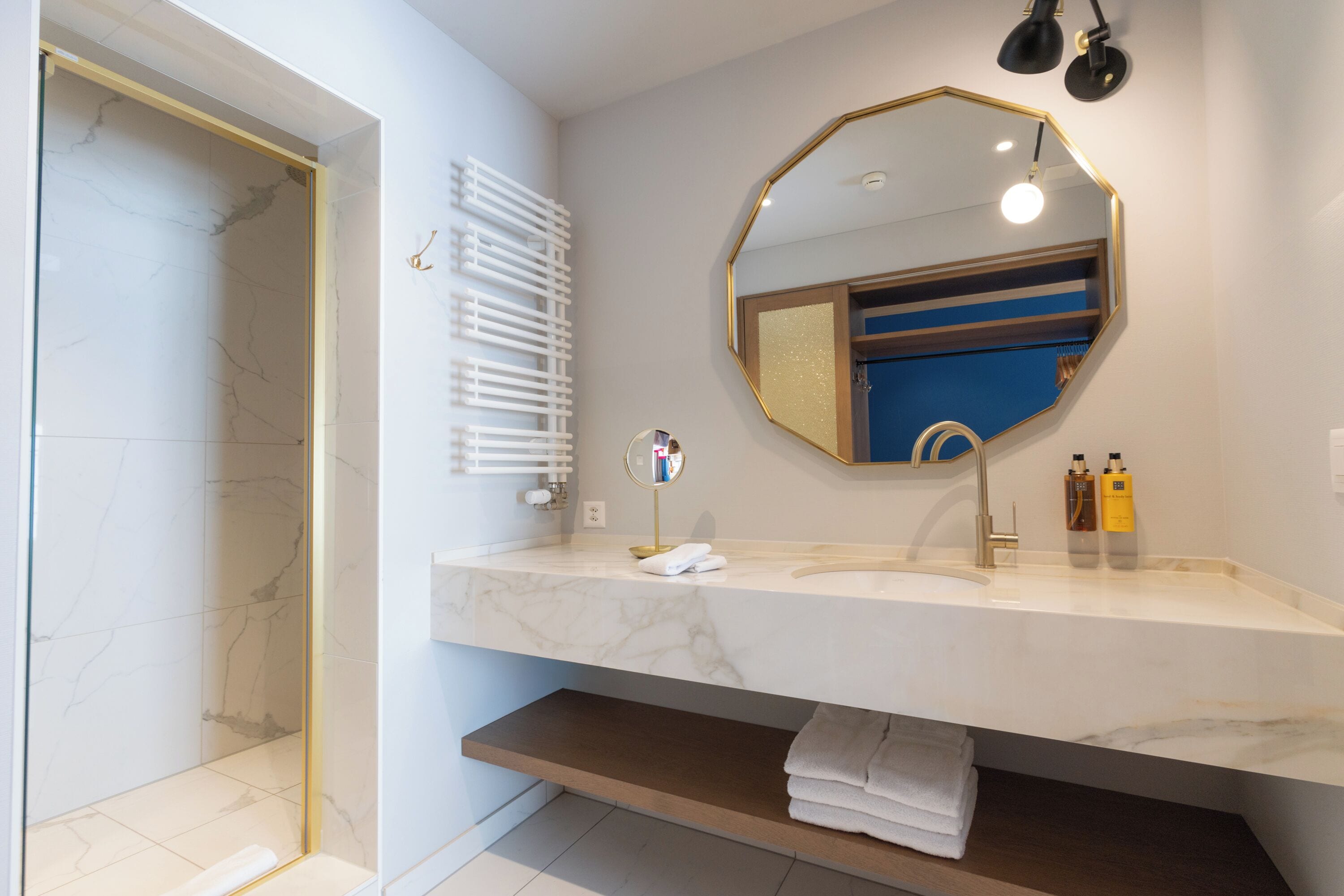 A modern bathroom with a marble vanity, a large mirror, and a towel rack.