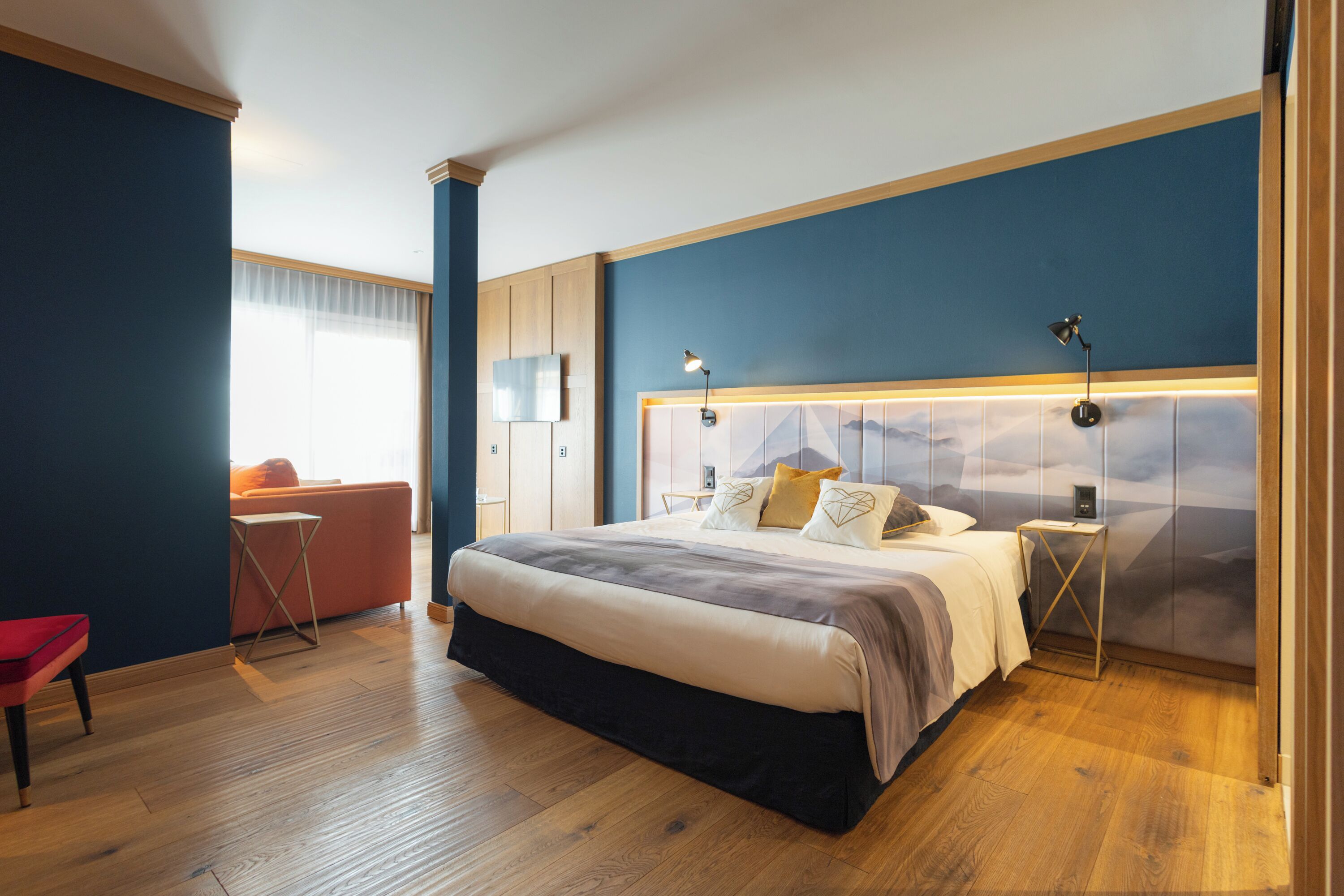 Een moderne slaapkamer met een groot bed, nachtkastjes, een bureau en een stoel.