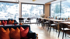 Un espace de restauration moderne offrant une vue sur un paysage montagneux enneigé.