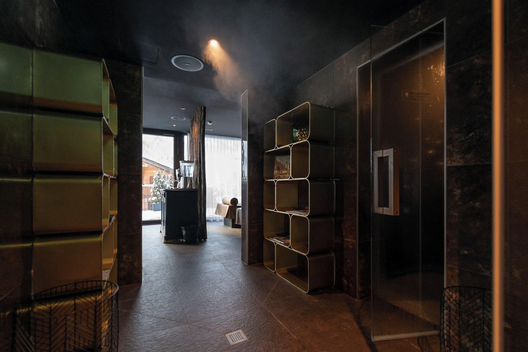 Een modern interieur met een centraal geplaatste open haard, een houten salontafel en een boekenkast.