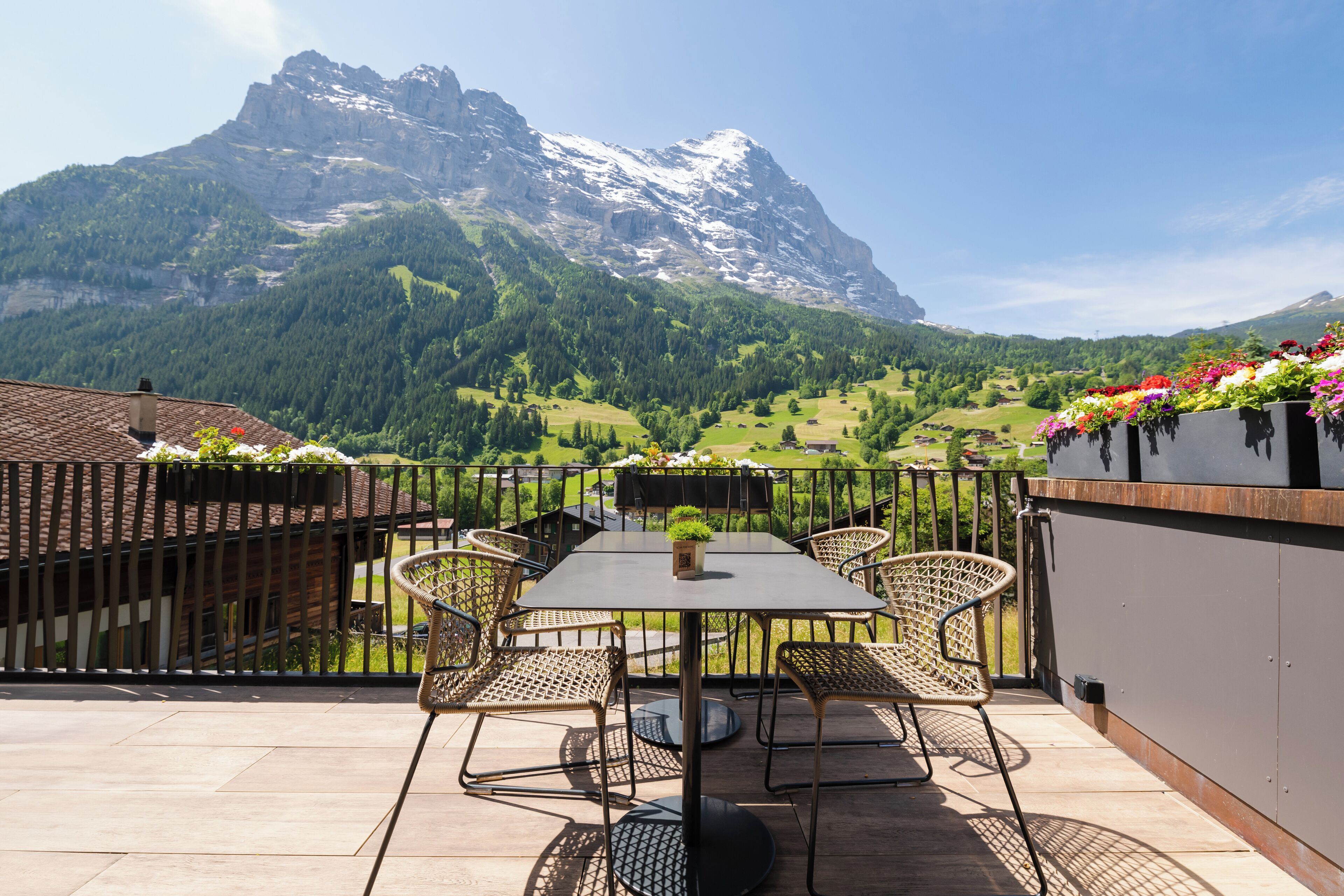 A terrace with a table and chairs, overlooking a mountainous landscape.
