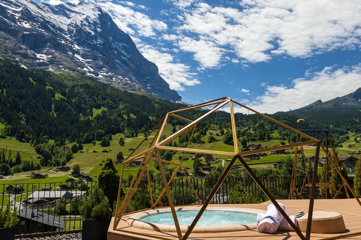 A pool area with a wooden deck and a view of a mountainous landscape.