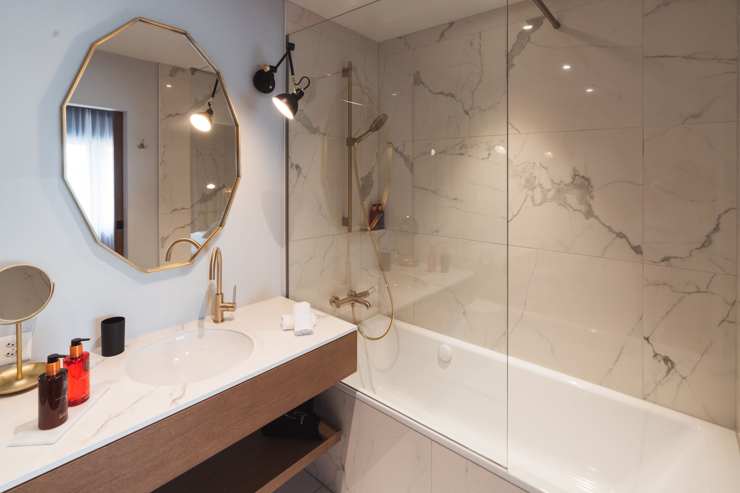 A bathroom with a large mirror, a sink, and a bathtub.