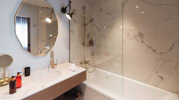 A bathroom with a large mirror, a sink, and a bathtub.
