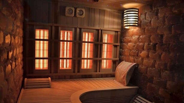 Una sauna con bancos de madera, paredes de piedra y techo inclinado.