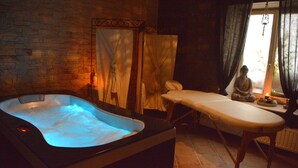 Un cuarto de spa con un jacuzzi, una camilla de masaje y un ventanal con cortinas.