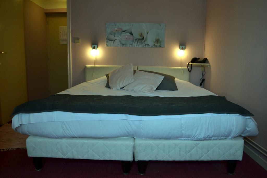 A double bed with two pillows, a dark blanket, and a wall-mounted phone.