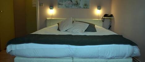 A double bed with two pillows, a dark blanket, and a wall-mounted phone.