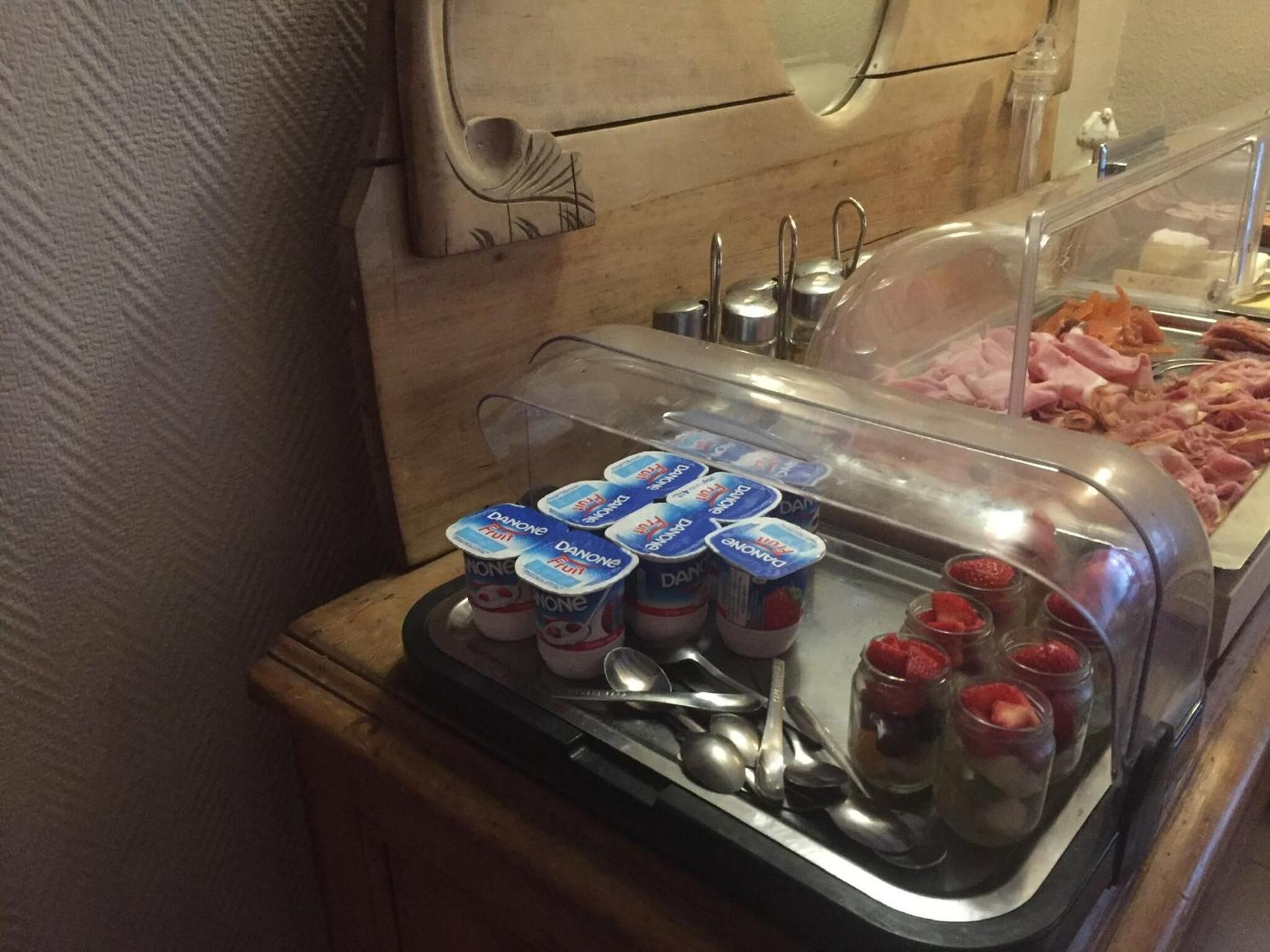Un buffet de petit-déjeuner comprenant des yaourts, des fraises et diverses sortes de charcuterie.