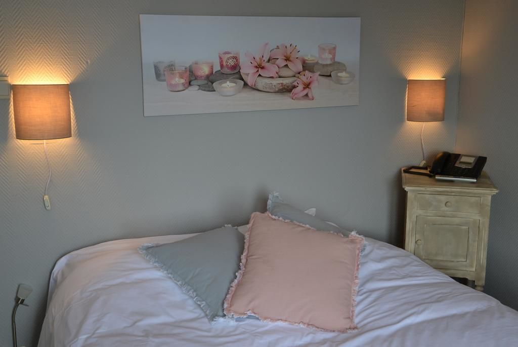 A bedroom with a bed, pillows, a nightstand, a lamp, and a wall-mounted artwork.