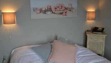 A bedroom with a bed, pillows, a nightstand, a lamp, and a wall-mounted artwork.