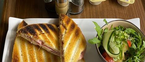 A sandwich on a tray with condiments and a salad.