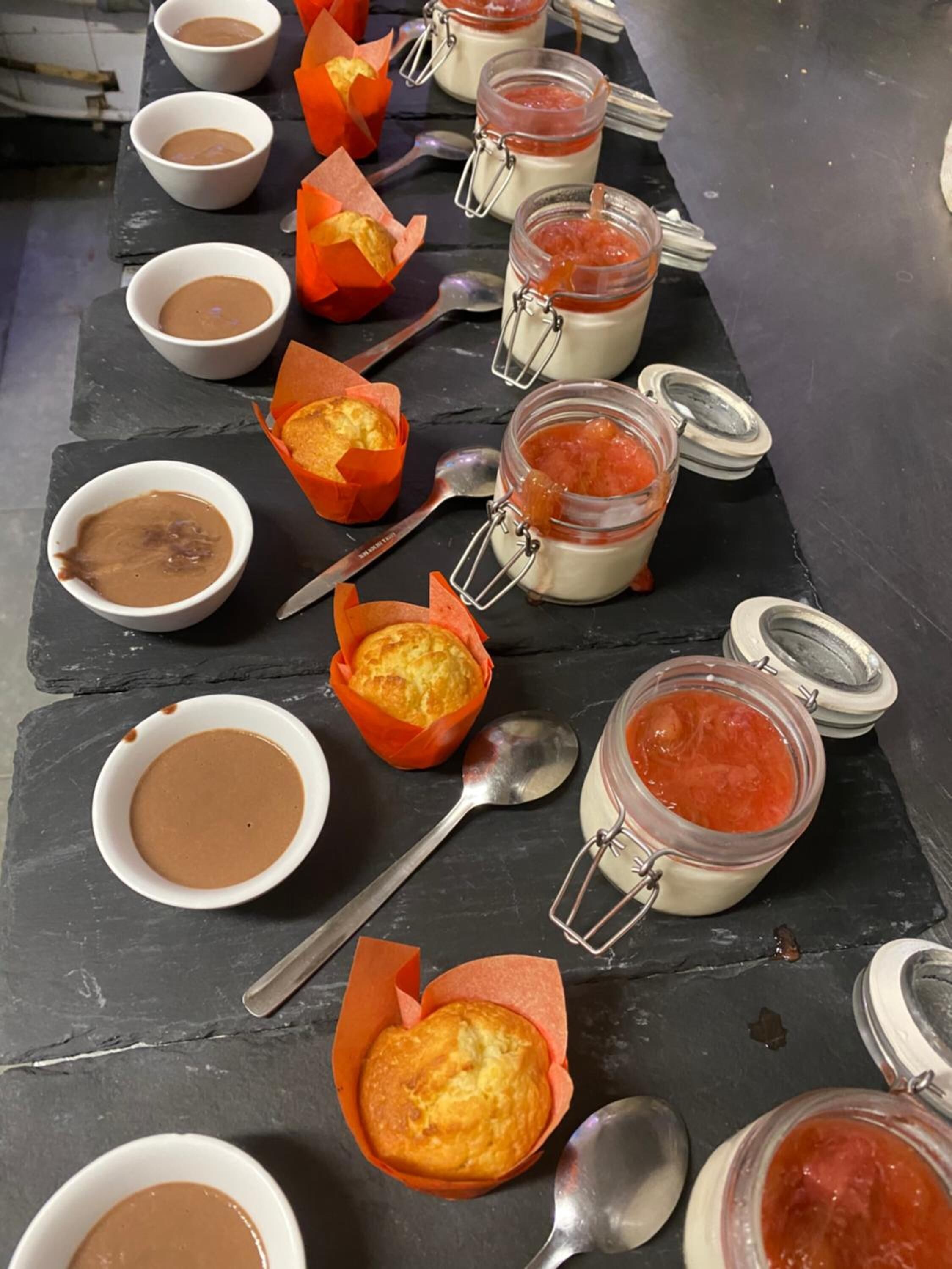 Variedad de alimentos, entre ellos productos horneados y salsas, sobre una superficie de pizarra.