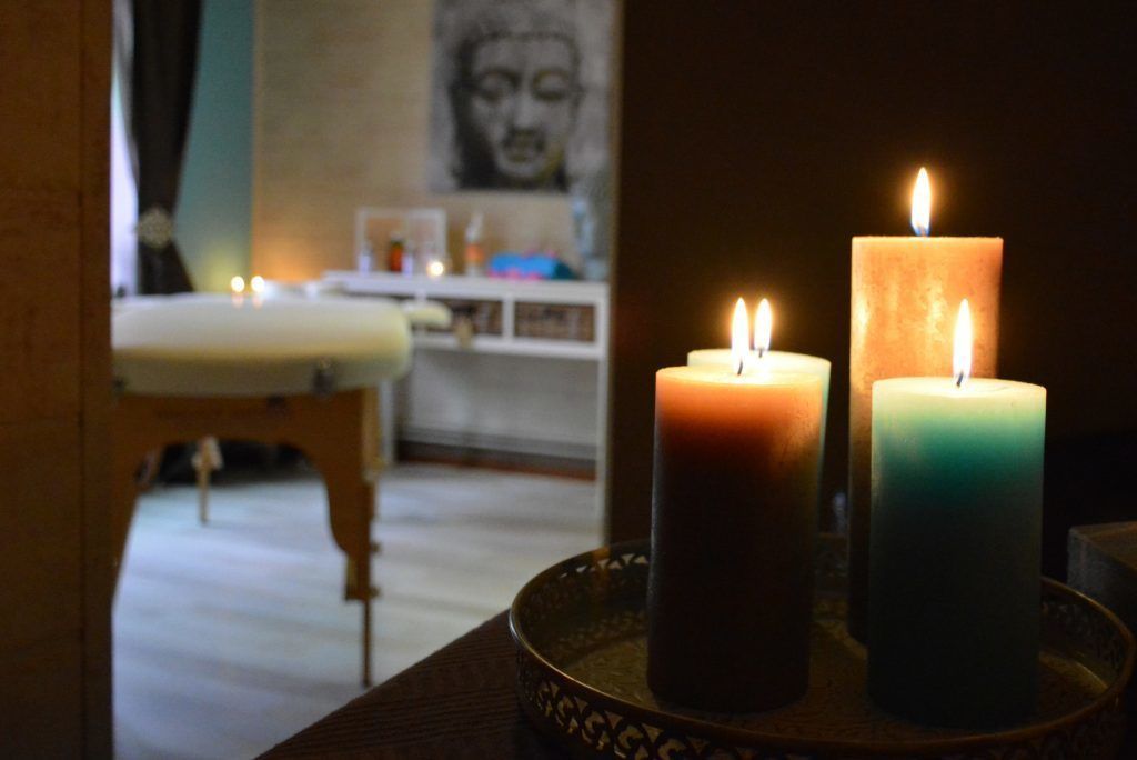 Een kamer met een houten stoel en een tafel met drie kaarsen.