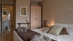 Un dormitorio con cama, mesita de noche, armario y baño visible a través de una puerta abierta.