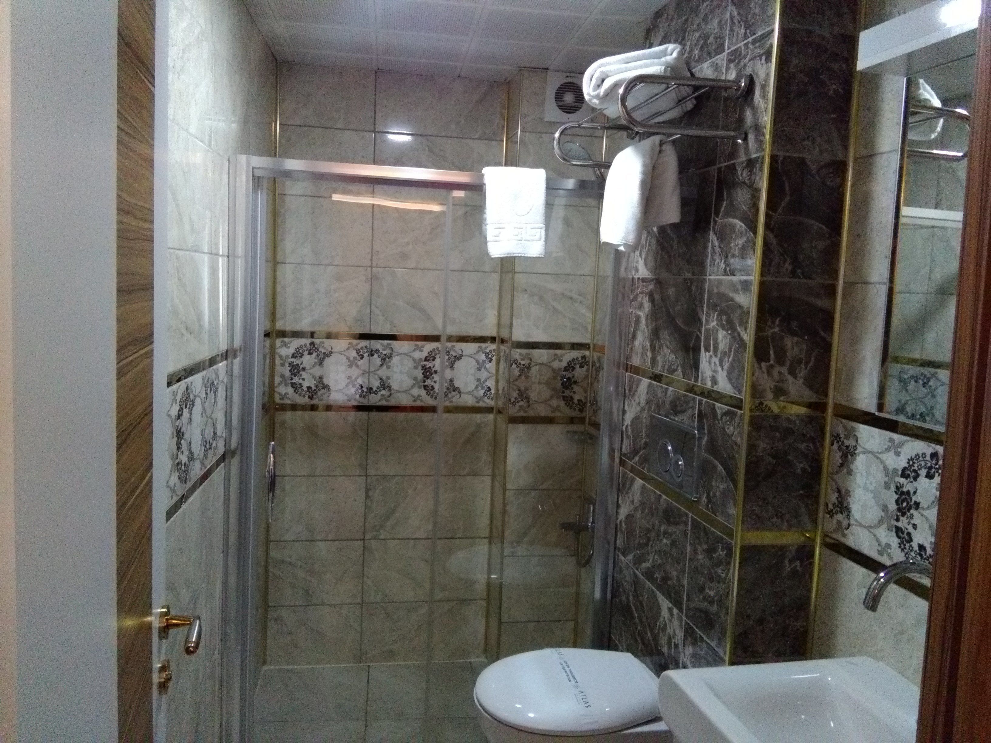 A bathroom with a glass-enclosed shower, a toilet, and a sink.