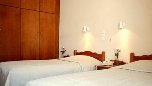 Ein Hotelzimmer mit zwei Einzelbetten, Holz-Kopfteilen, Nachttischen mit Lampen und einem großen Kleiderschrank.