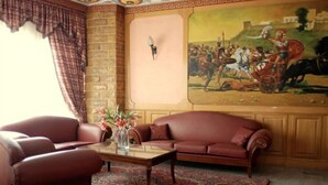 Ein Wohnzimmer mit einer Couch, Sesseln, einem Couchtisch und einem Gemälde an der Wand.