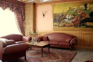A living room with a sofa, armchairs, a coffee table, and a painting on the wall.