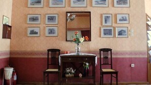 Ein Zimmer mit einem Tisch, zwei Stühlen, einem Spiegel und einer Wand mit gerahmten Bildern.