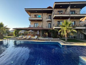 A multi-story hotel with a swimming pool, outdoor seating, and a covered patio area. - Kuzey Park Hotel Arc en Ciel (Gökçeada)