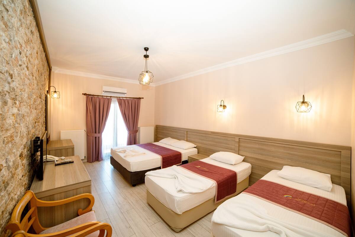 Habitación de hotel con tres camas, un escritorio y una silla.