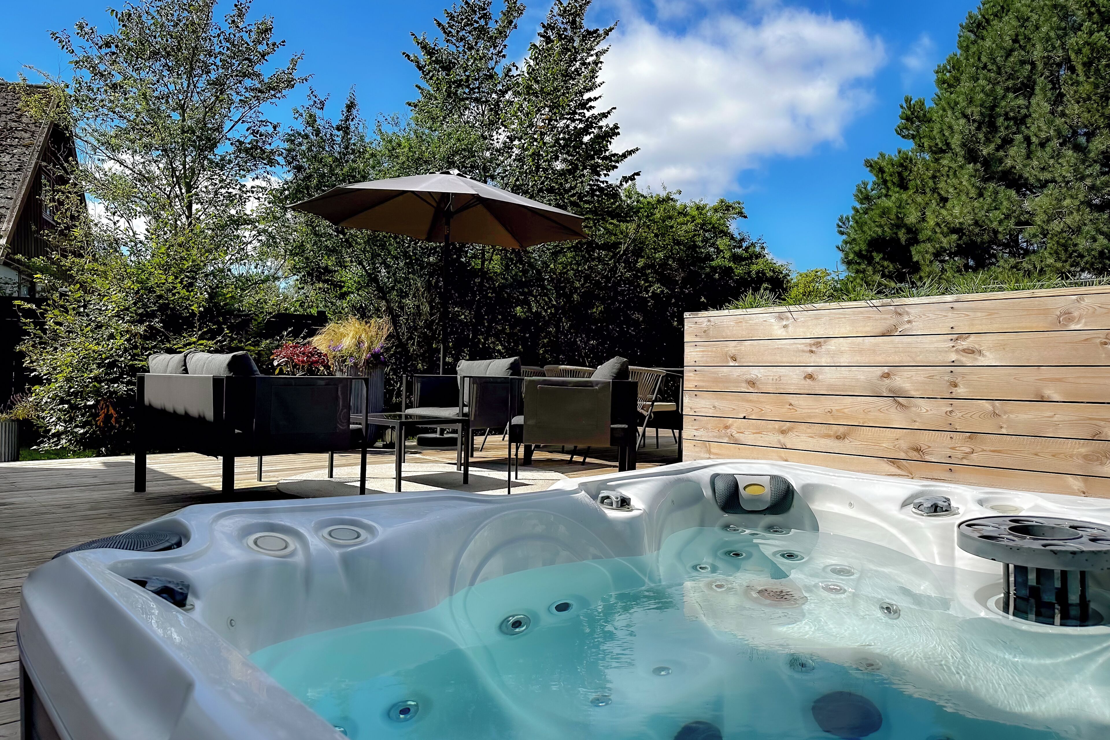 Un jacuzzi con plataforma de madera, muebles de exterior y cerca de madera.