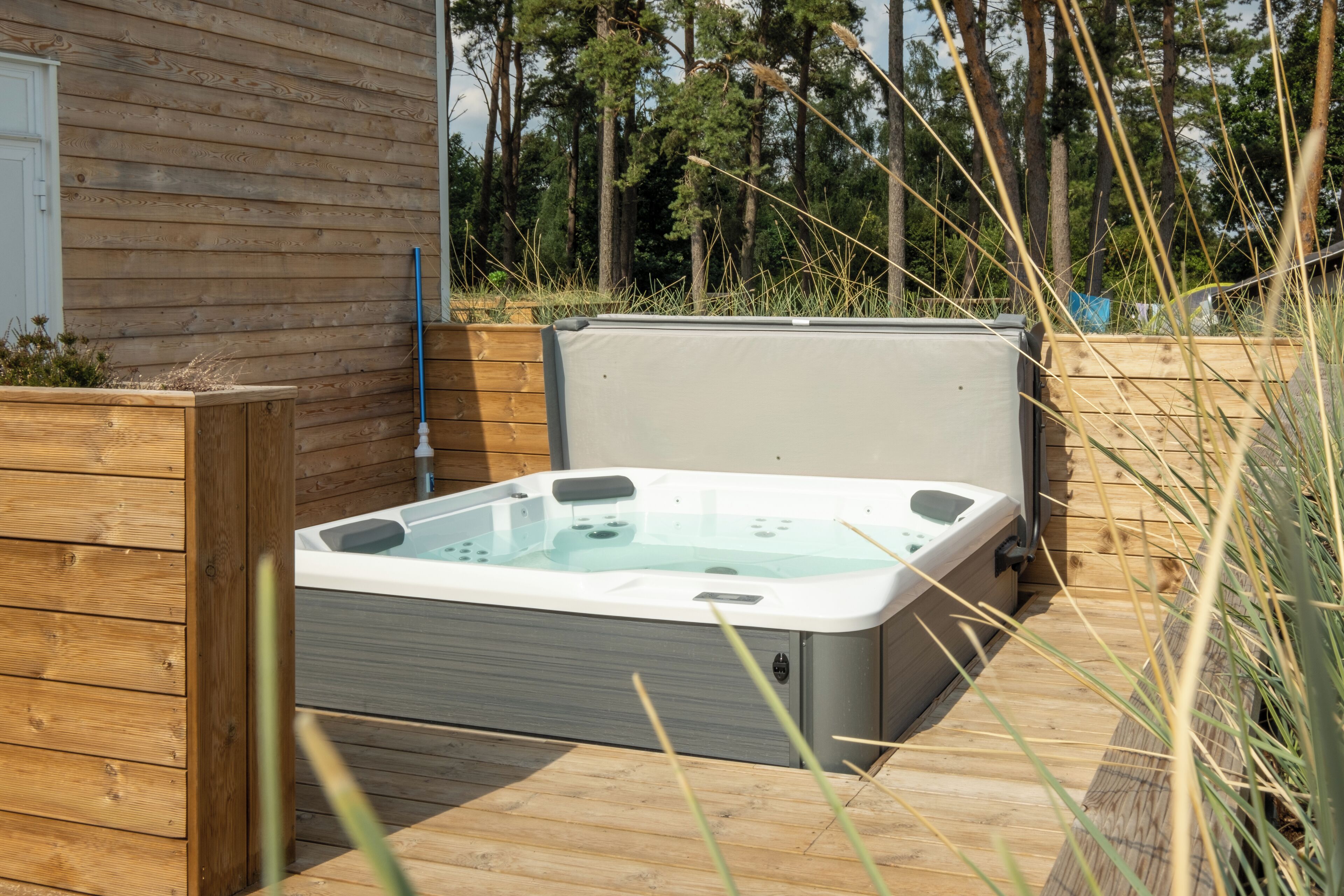 A hot tub in an outdoor setting with wooden decking and a wooden fence.