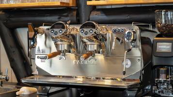 A professional espresso machine with a digital display and wooden handles, placed on a commercial kitchen counter.