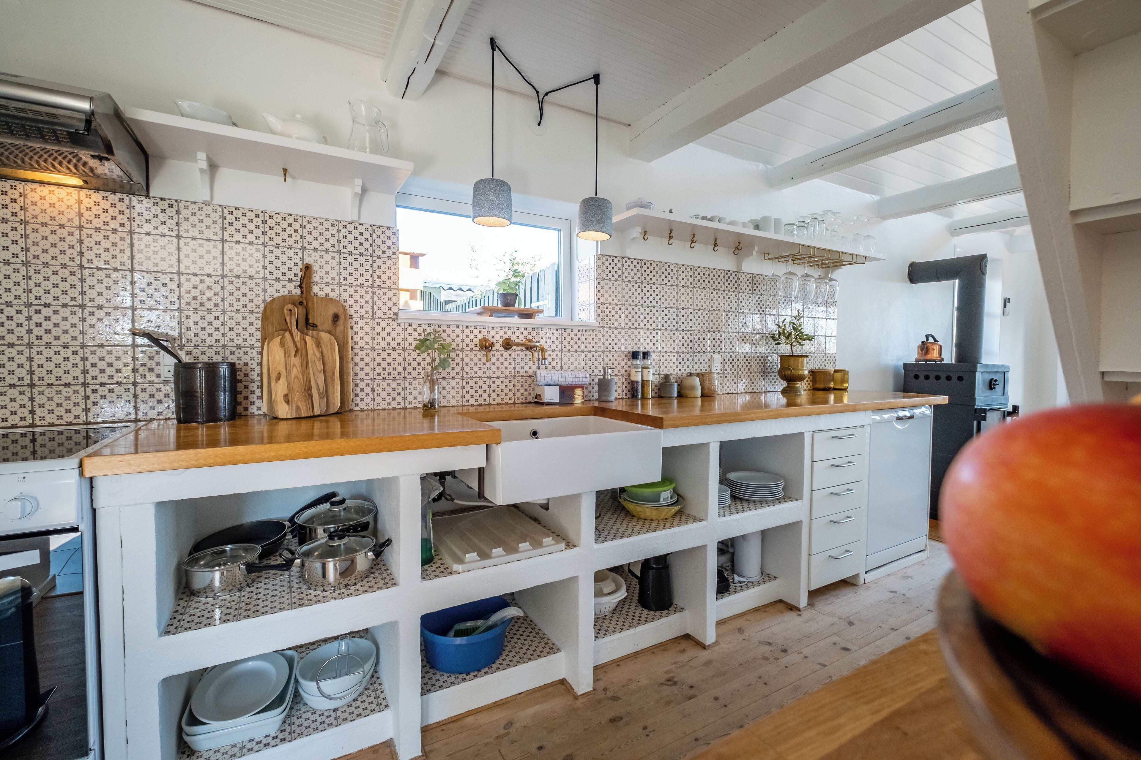 Una cocina con armarios blancos, encimera de madera y ventana con vistas.