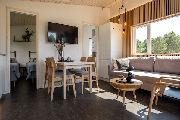 Una sala de estar moderna con comedor, un sofá y un televisor montado en la pared.