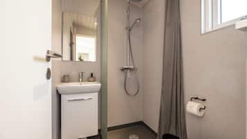Un baño pequeño con inodoro, lavabo, ducha y espejo.