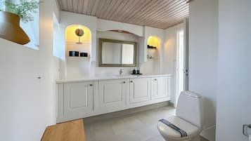 Um banheiro moderno com toucador branco, um espelho grande e um vaso sanitário.