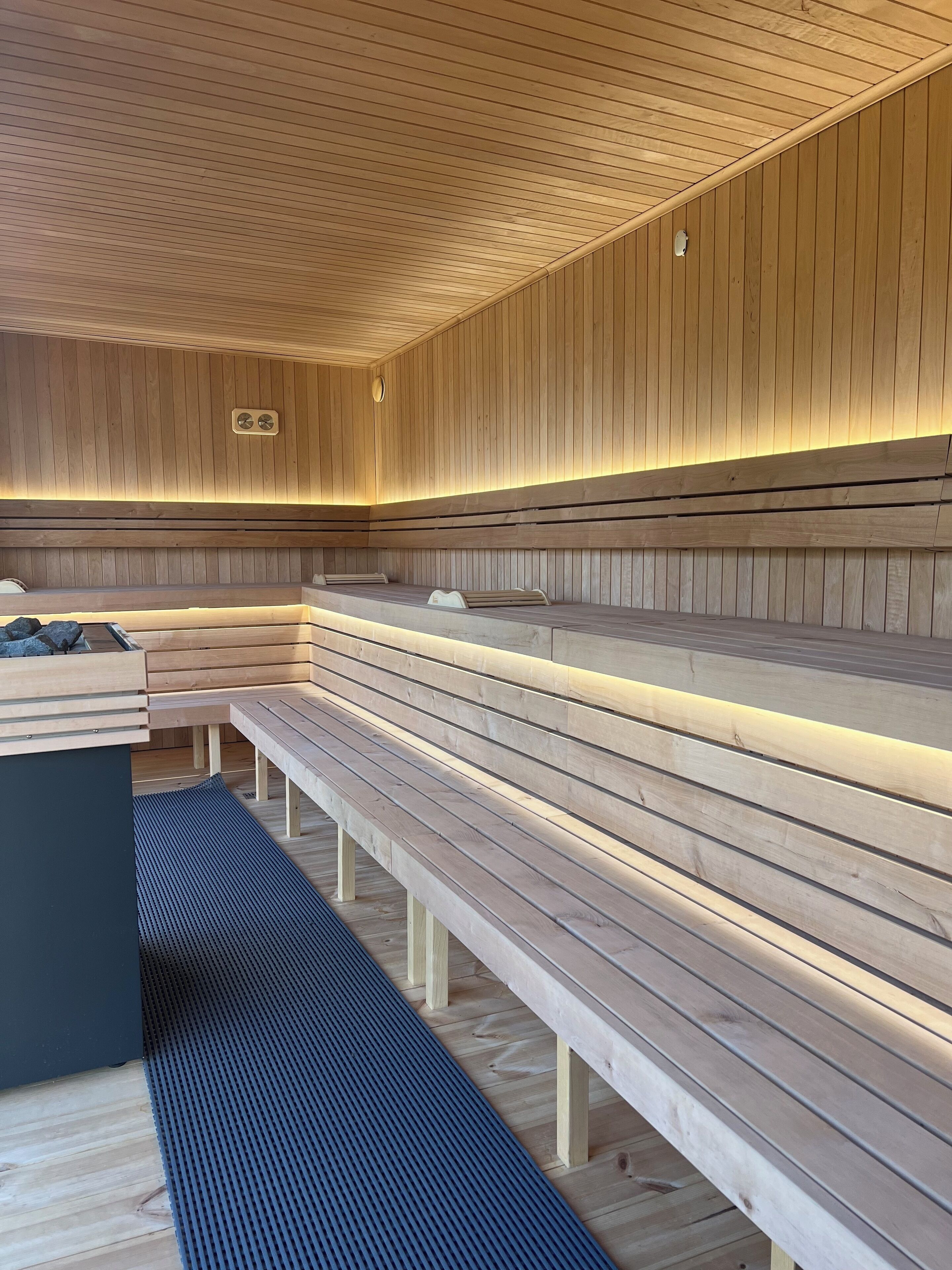 Un sauna avec des bancs en bois et un banc équipé d’un fauteuil de massage.