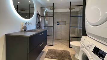Un baño moderno con tocador, inodoro, ducha y lavadora.