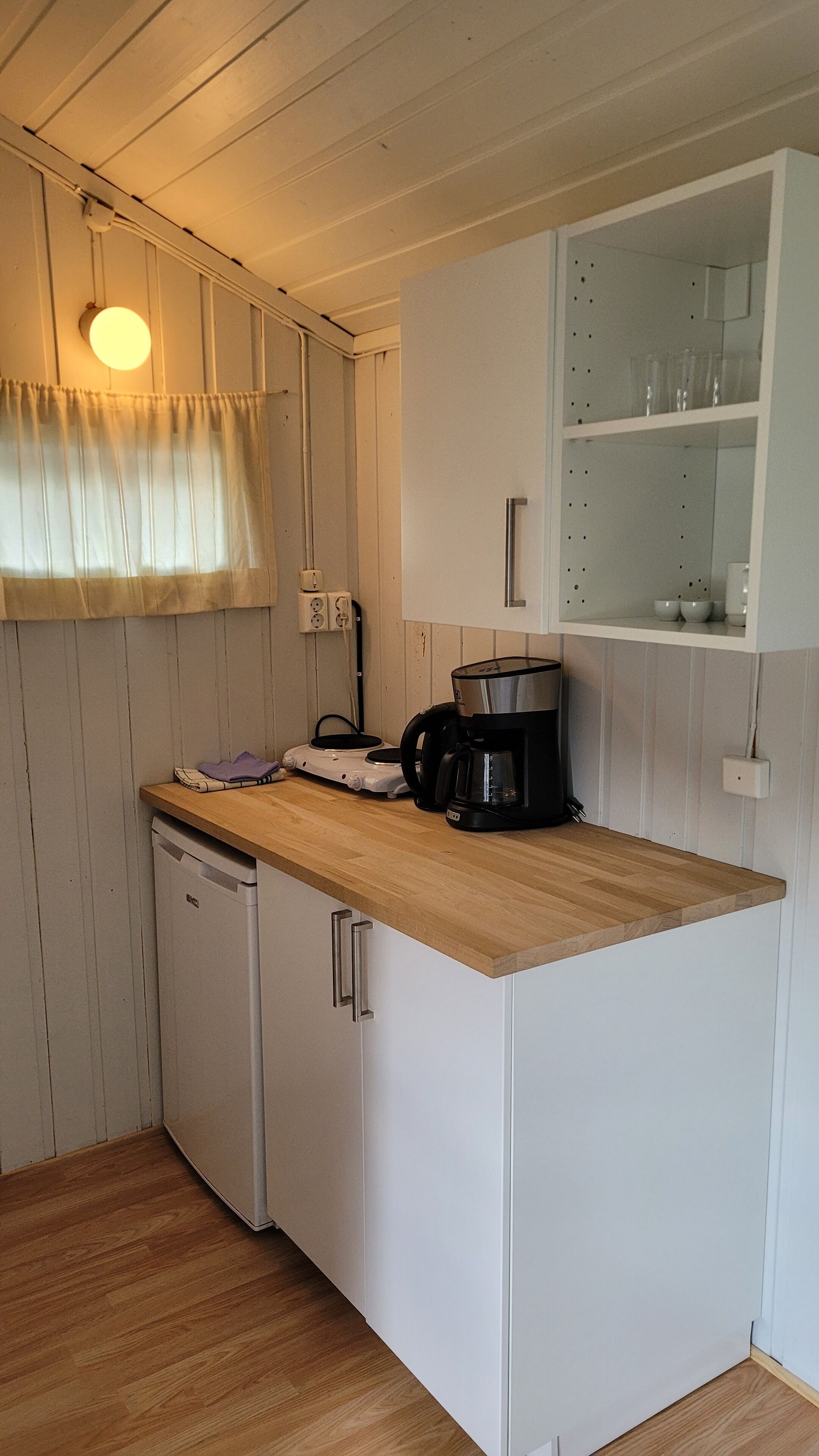 A compact kitchen with a wooden countertop, a coffee maker, and a dishwasher.