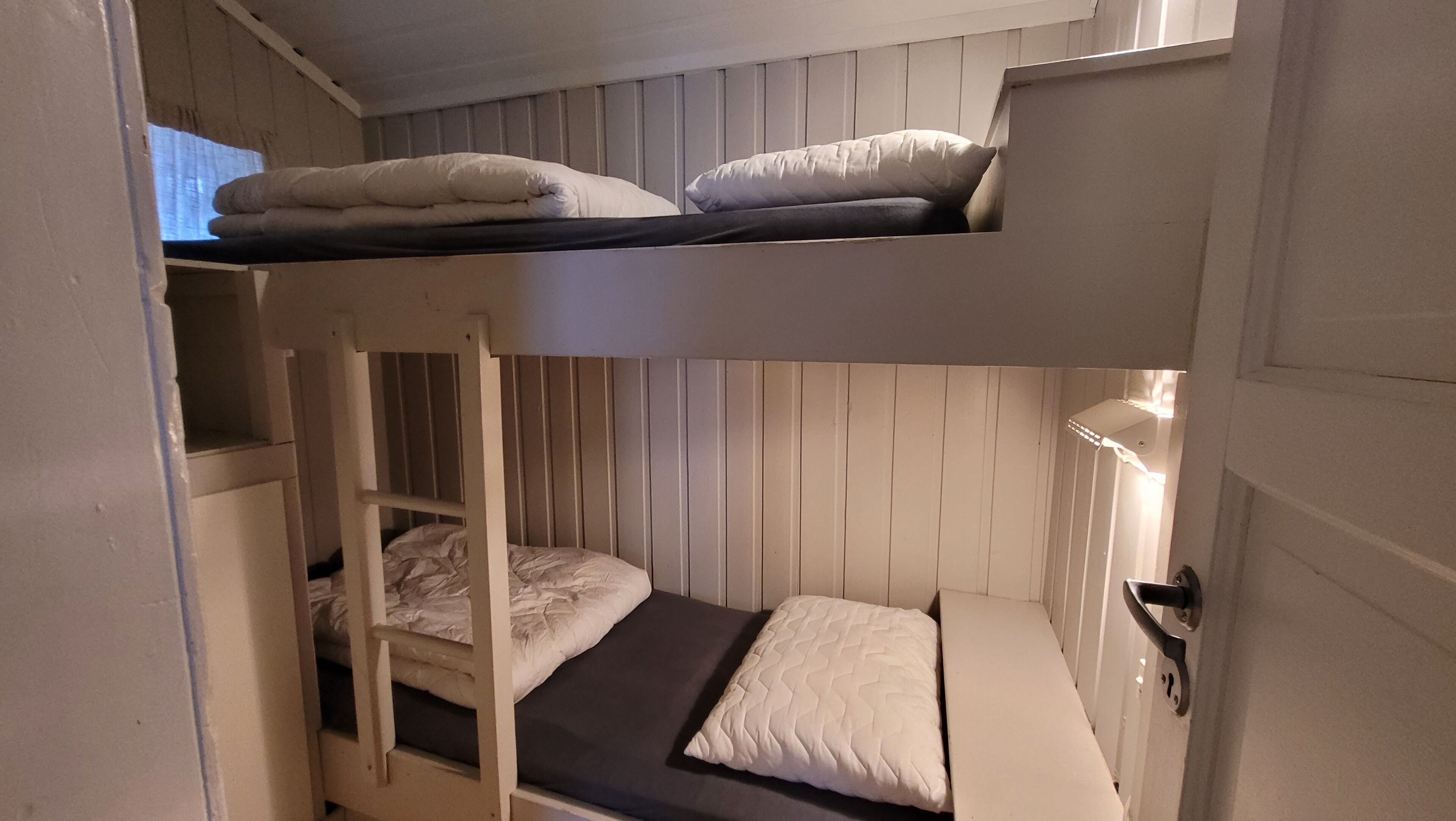 Kerrossängyllä varustettu huone, jossa on myös tikkaat, työpöytä ja yöpöytä.