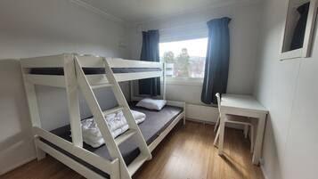 A bunk bed room with a desk and a window.