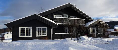 Eine zweistöckige Holzhütte mit einem Balkon, umgeben von Schnee.