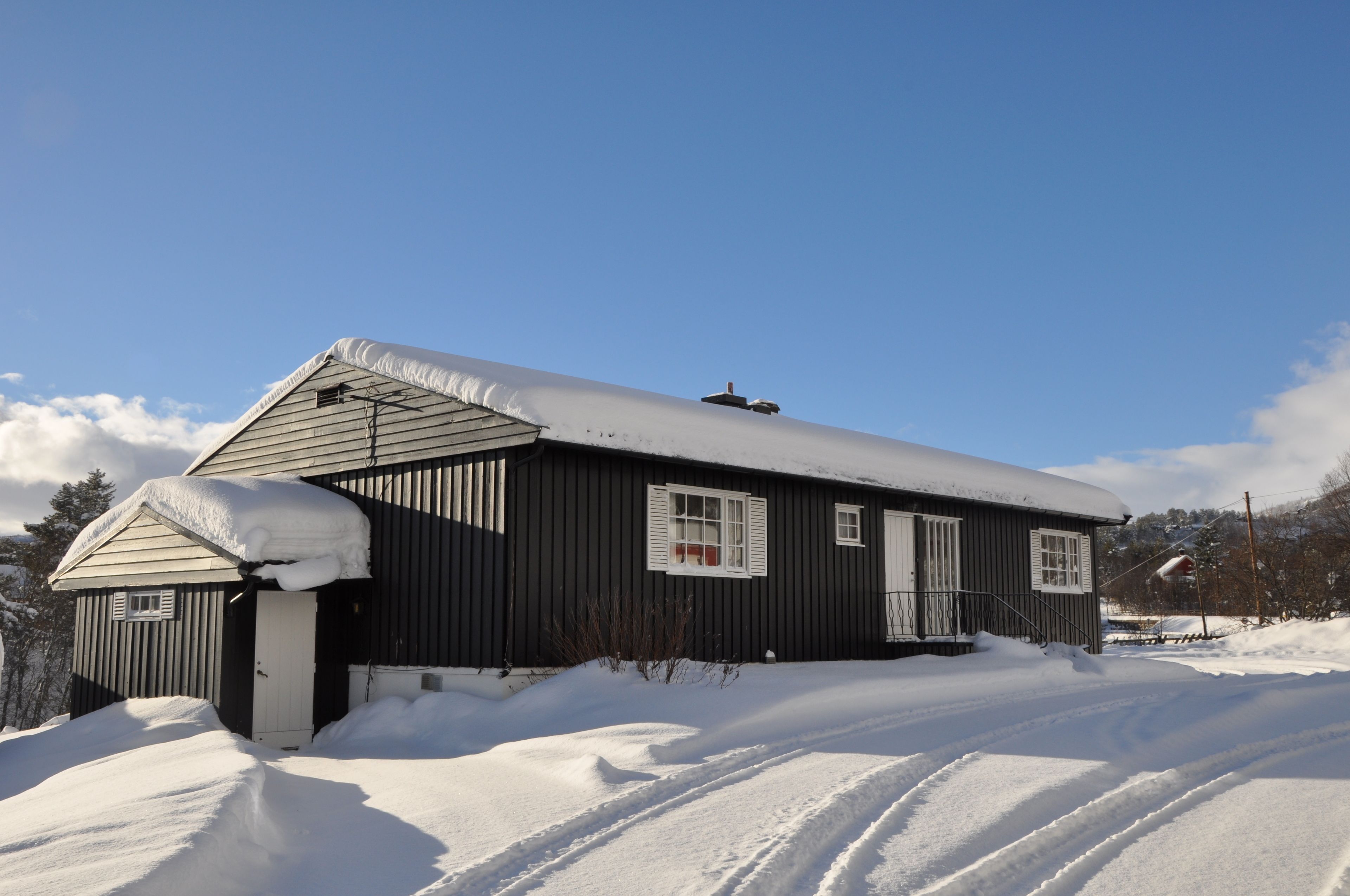 A single-story building with a dark exterior and a snow-covered roof.