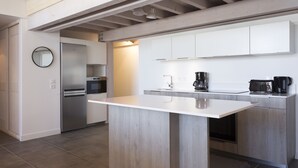 Uma cozinha moderna com ilha central, eletrodomésticos embutidos e teto de madeira.