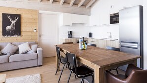 Uma cozinha moderna com uma mesa de jantar de madeira, cadeiras pretas e uma geladeira branca.