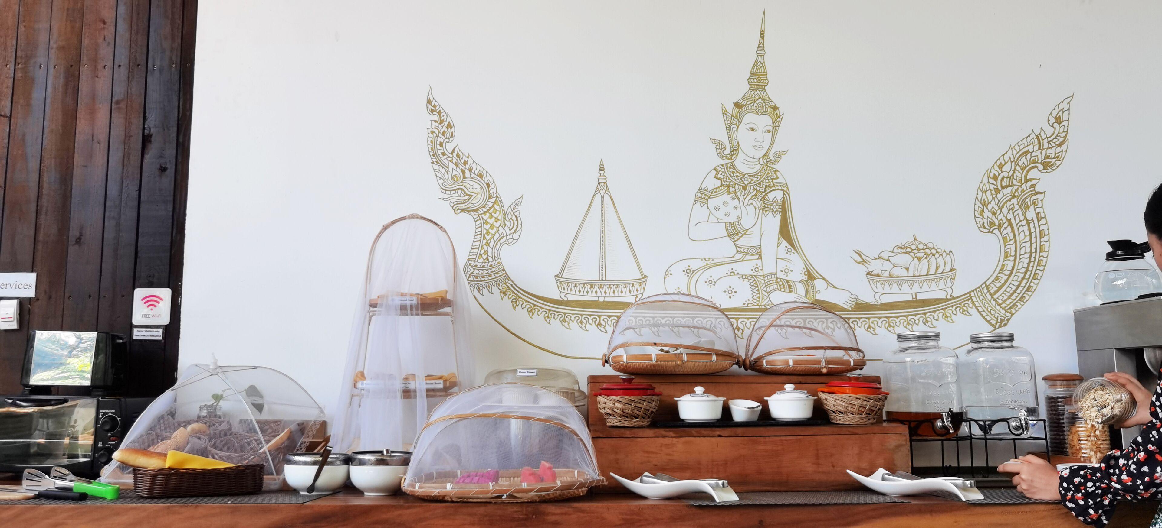 A counter with food items, a decorative wall with a golden design, and a person serving.