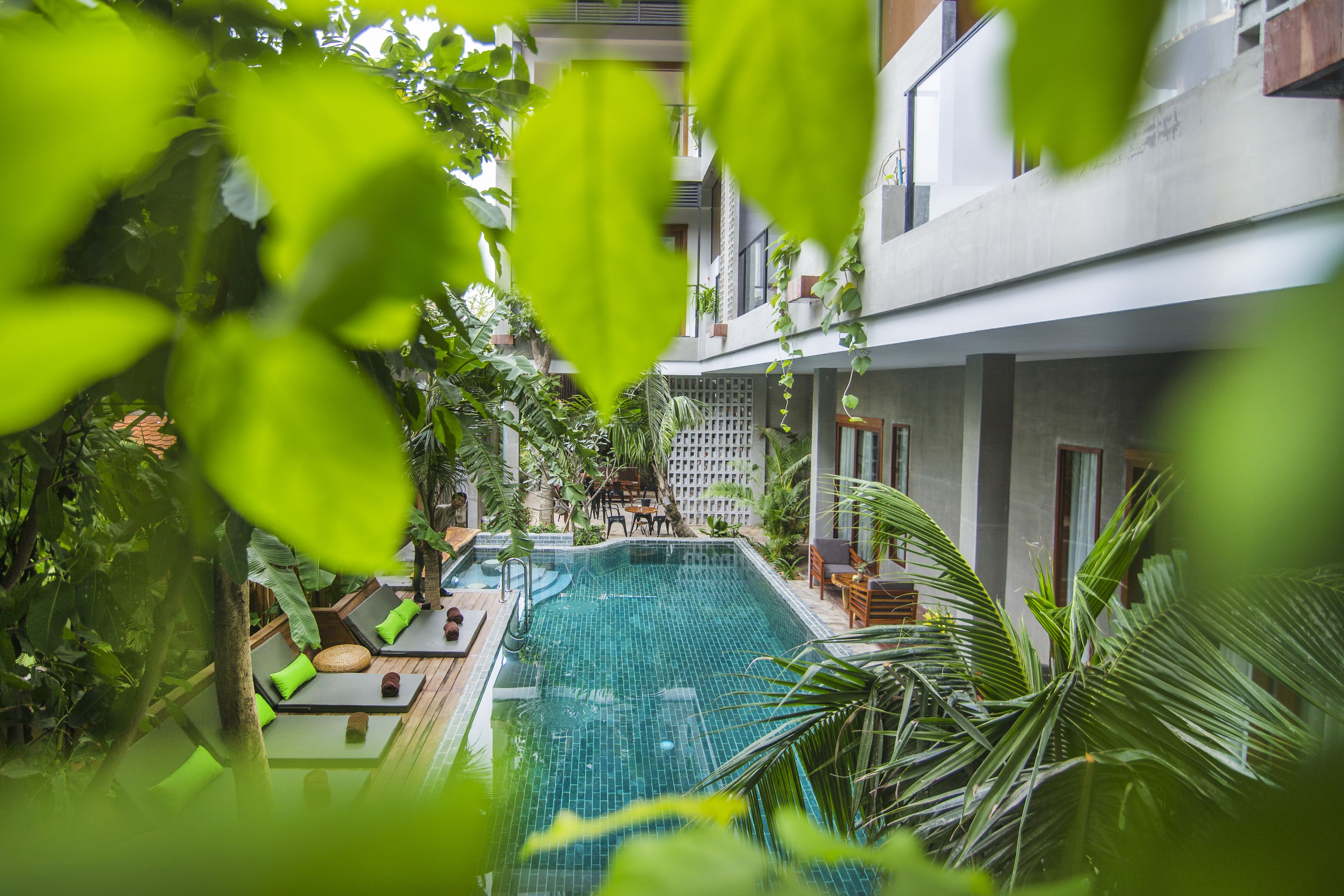 An indoor swimming pool with lounge areas, surrounded by greenery and modern architecture.